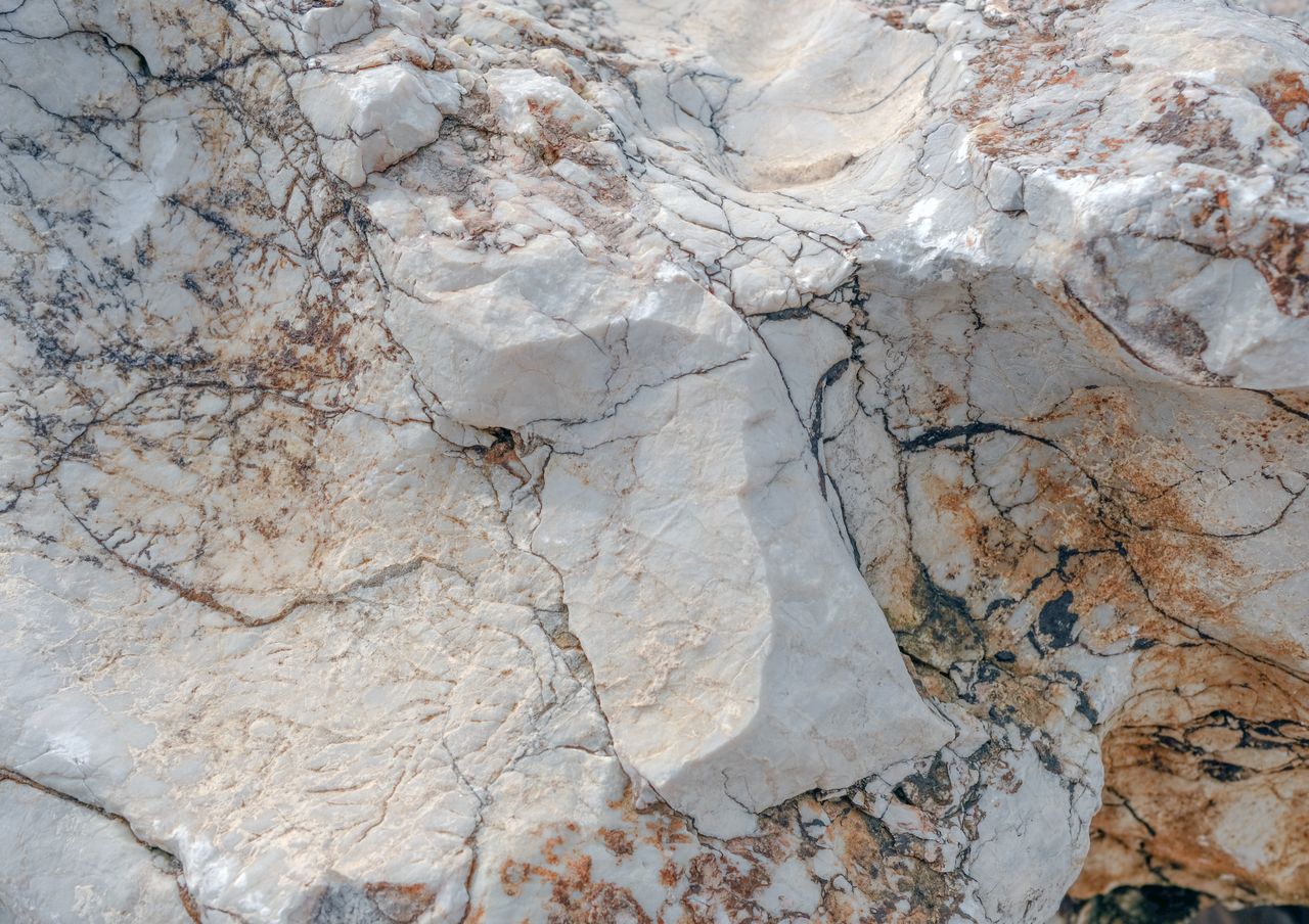 Detailed view of a weathered marble rock surface showing natural patterns and textures.